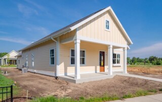 new yellow home with white pillars and unfinished lawn