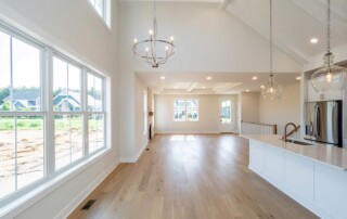 high ceiling room with large windows and kitchen on the side