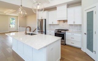 white kitchen island with glass light fixtures and storage in background