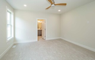 room with wood ceiling fan and door leading to bathroom