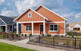 orange home behind black metal fence and sidewalk