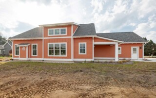 orange house with white trim and unfinished lawn