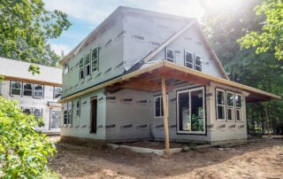 unfinished two-story home in freshly cleared lot surrounded by trees