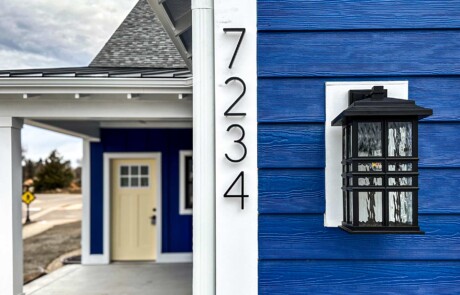closeup of house numbers and lantern on corner of blue sided house