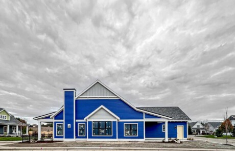distant view of blue custom home under striking cloudy sky