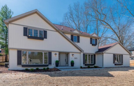 angled view of front of 2-story white home with brown accents