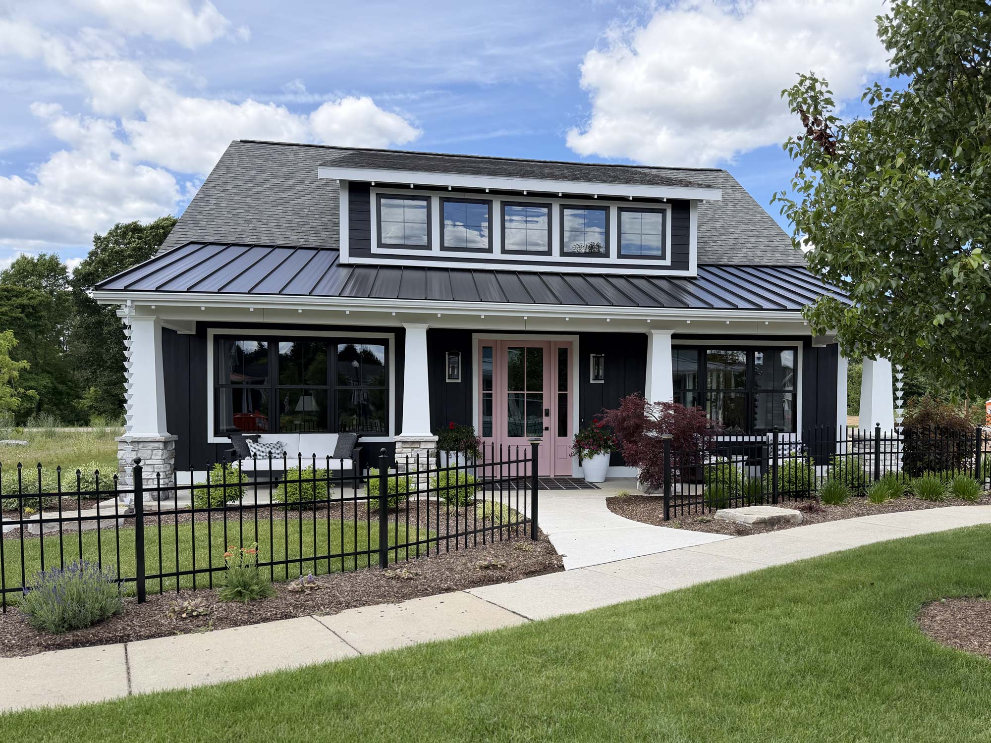 front exterior view of black cottage with upper row of windows
