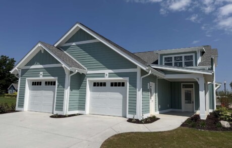 view up driveway to garage of blue-green home