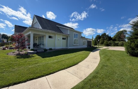 angled view of green and yellow home with sidewalk